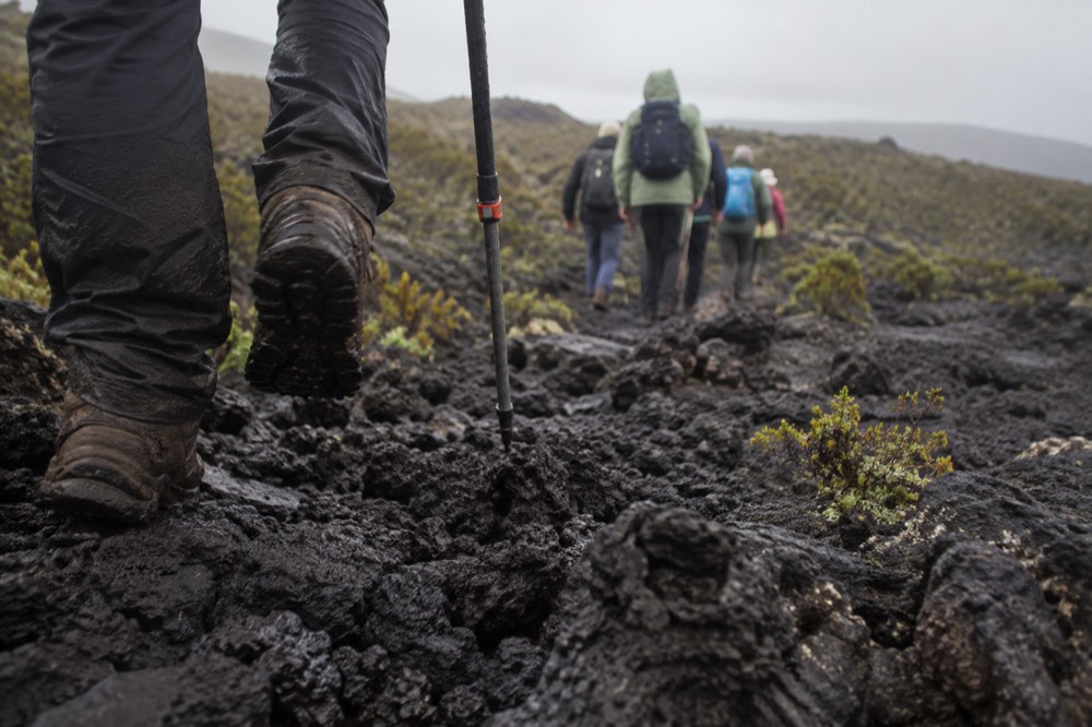 Low morning drizzle on Sierra Negra trail, Galapagos Islands, a small budget tour group blurred beyond on the wet path