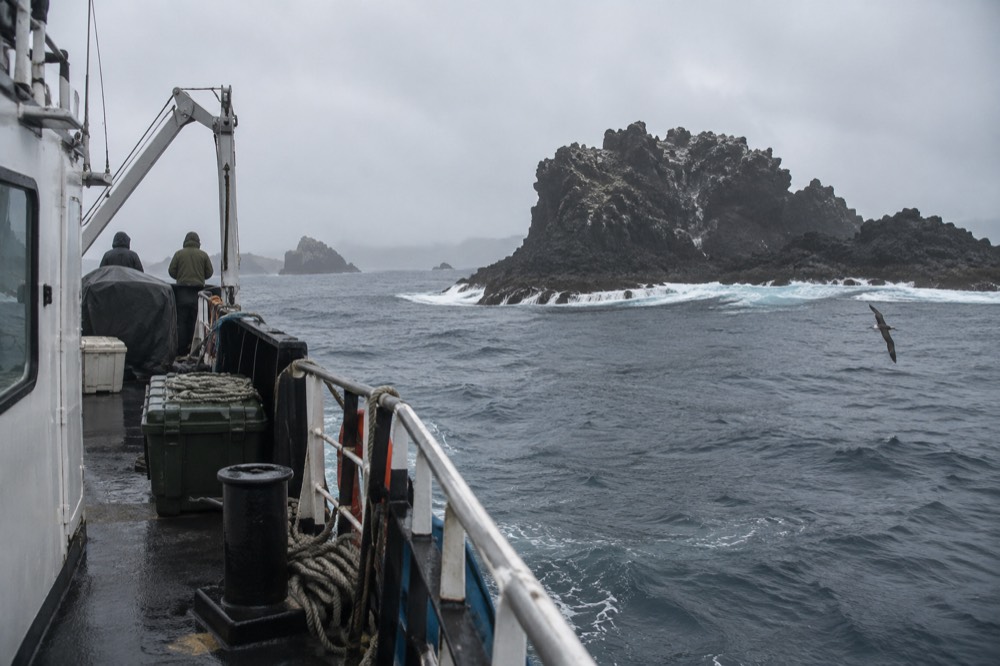 Open Pacific off the Galapagos Islands, Ecuador, cool season: a small steel expedition vessel rides a slow swell past a black lava headland