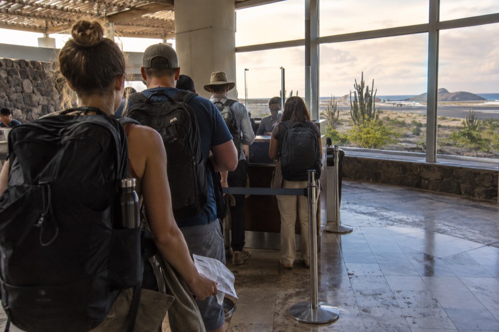 Late afternoon in Seymour Airport's arrivals hall on Baltra in Ecuador's Galapagos, travellers from behind queuing at a payment counter
