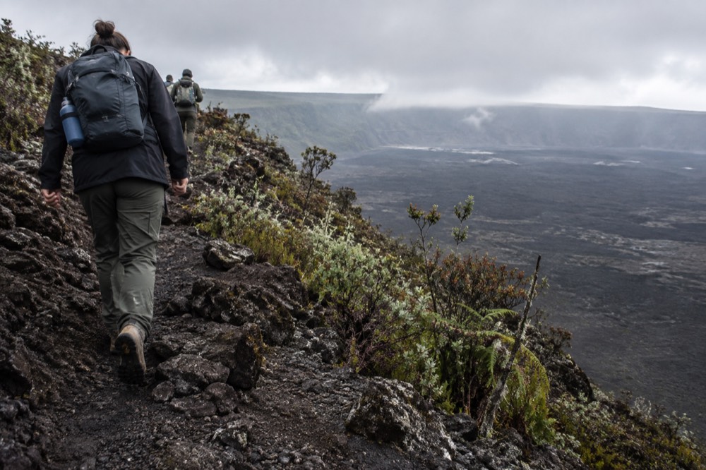 Hikers from behind on Isabela Island in Ecuador's Galapagos climbing Sierra Negra's trail toward the vast caldera rim
