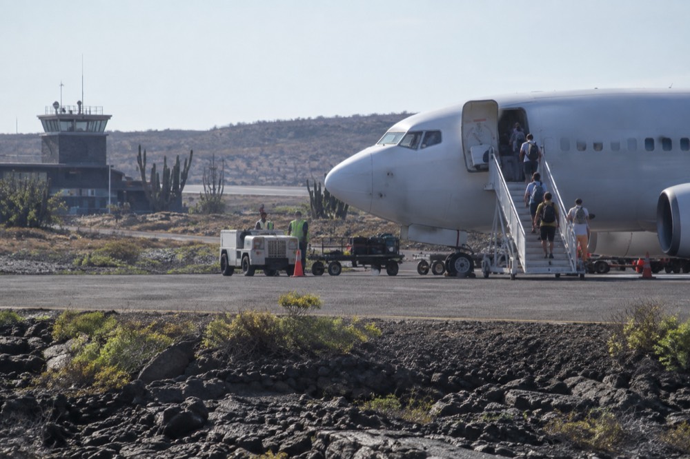 A jet stands on the tarmac at Seymour Airport in the Galapagos Islands, Ecuador, its steps down onto black lava and crushed volcanic gravel