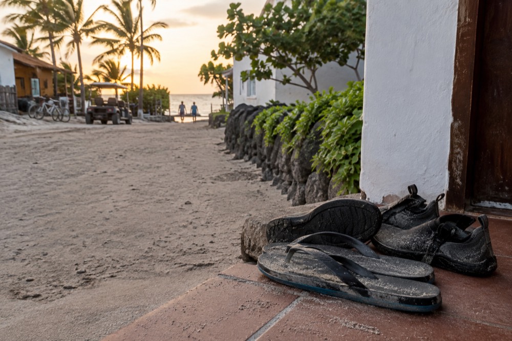 Flip-flops and water shoes drying on a coral-sand doorstep in Puerto Villamil, Galapagos Islands, Ecuador